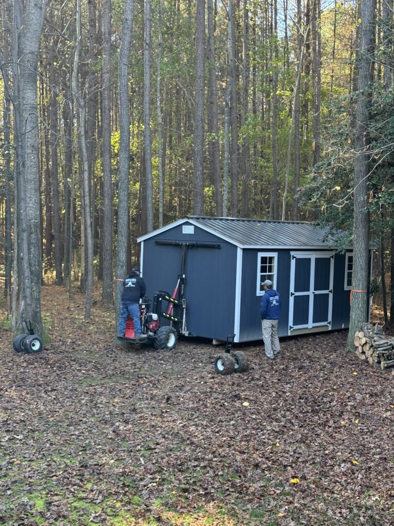 Shed Site Preparation: Picture of the delivery guys using a skid steer to place the shed office on the prepped land. 
